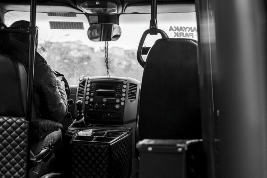 Een buschauffeur rijdt door een Nederlandse stad met een glimlach, onderweg met passagiers in een moderne bus.